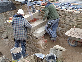 Zwei Bauarbeiter setzen Steintreppenstufen ein ein 