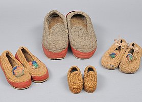 Das Bild zeigt vier Paar Schuhe aus Stroh.