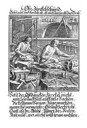 Das Bild ist über 300 Jahre alt. Es zeigt eine Werkstatt. In der Werkstatt arbeiten zwei Schmiede. Sie stellen Zirkel und andere Werkzeuge her. Vorne ist ein Amboss. Bei dem Amboss liegen Hämmer. Hinten ist eine Esse.