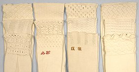 Die vier Paare Socken sind weiß. Sie sind mit farbigen Buchstaben bestickt.