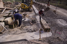 Bauarbeiter errichten Stück für Stück eine massive Steinmauer