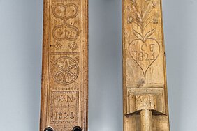Die Mangelbretter sind noch einmal näher zu sehen. Sie sind stark verziert. Sie zeigen Muster, Blumen, Ranken, Sterne, Jahreszahlen und Buchstaben.