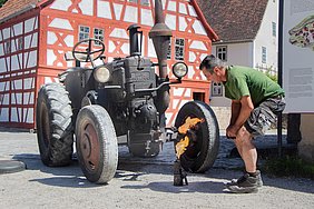 Mechaniker vor altem Lanz-Bulldog, mit Brenner zum Anglühen 