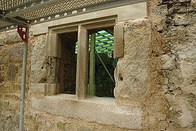 Fotoaufnahme der Nordfassade nach Einbau der Fenstergewände. Im Fokus steht ein Fenster mit einem Sandsteinmittelsteg, An der linken und rechten Seite wird das Fenster jeweils von einem Sandsteinquader abgeschlossen. An dem Sandsteinmauerwerk steht ein Gerüst. 