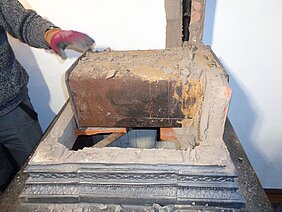 Der Ofen wird für das Museum abgebaut. Er wird Stück für Stück auseinander genommen. Hier ist eine Röhre aus Eisen zu sehen. In der Röhre konnte man Essen heiß machen.