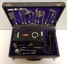 Ein schwarzer, aufgeklappter Koffer, gefüllt mit einem schwarzen kastenförmigen Messgerät mit Kabel und zahlreichen Aufsätzen aus Glas 