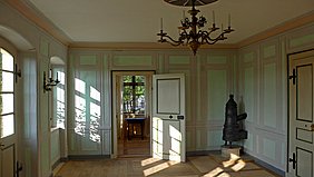 heller Schlosssaal mit Kronleuchter und Türen