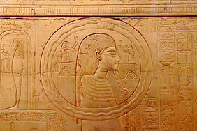Ein Uroboros kreist um den Kopf des Sonnengottes, der mit Götterbart, Halskragen und Perücke abgebildet ist.