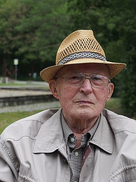 Älterer Mann mit Hut und Brille.