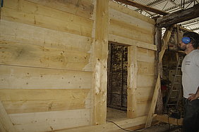 Eine im ersten Obergeschoss eingebaute Bohlenstube aus unbehandelten Pfostenständern und acht Bohlen in der Höhe, außerdem eine Türen