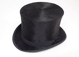 Der Hut ist schwarz. Er hat die Form eines Zylinders.