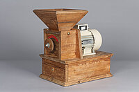 Die Mühle ist aus Holz. Unten ist ein Kasten mit Schublade. Darauf ist ein kleinerer Kasten mit Drehrad. Oben auf dem kleineren Kasten ist ein Trichter. Neben dem kleineren Kasten ist ein Motor.