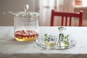 Waldmeister-Erdbeer-Bowle in einem Glastopf abgestellt auf einem Tisch.
