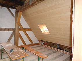 verbretterte Dachschräge mit kleiner Dachgaubenöffnung