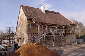 Das Badhaus aus Wendelstein mit nahezu abgebautem Gerüst. Davor ein Sandhaufen