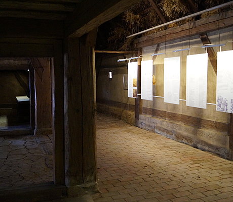 Texttaflen und mächtige Holzsäule im Inneren des Bauernhauses 