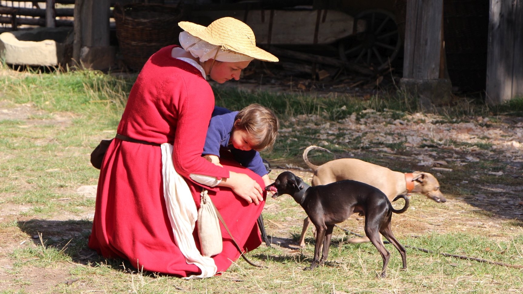 Eine Frau und ein Kind in mittelalterlicher Gewandung spielen mit einem kleinen Hund