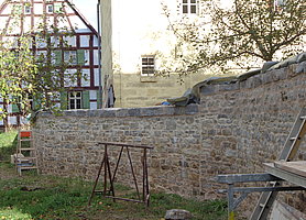 langgezogene Bruchsteinmauer mit großen Abdecksteinen, noch mit Baustelleneinrichtung