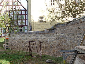 langgezogene Bruchsteinmauer mit großen Abdecksteinen, noch mit Baustelleneinrichtung