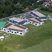 Fotoaufnahme des evangelischen Schullandheims aus der Vogelperspektive. Gezeigt werden fünf Gebäude mit Flachdach, daneben ist ein Sportplatz mit Fußballtoren. Das Schullandheim befindet sich in der Nähe vom Museumseingang. 