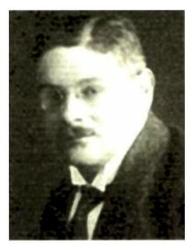 Schwarz-Weiß Fotografie eines jungen Mannes mit Schnurrbart, Krawatte und Brille.
