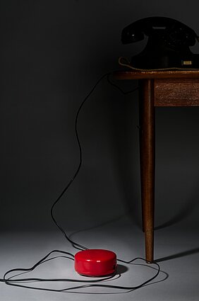 Der Telefonkabelaufroller liegt auf dem Boden. In ihm ist ein Telefonkabel eingelegt.