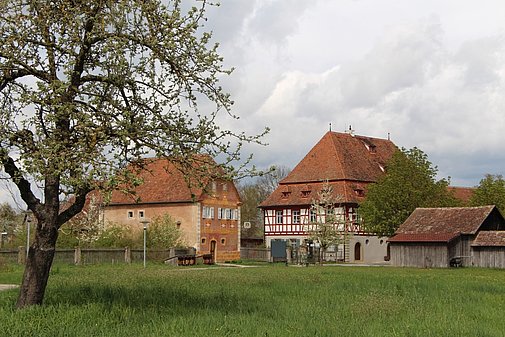 Das Gasthaus aus Oberamfrach, ein imposantes Fachwerkgebäude, daneben links das Korbhaus aus Knittelsbach, gelb verputztes, kleines Fachwerkhaus. Vor dem Gasthaus eine Kegelbahn