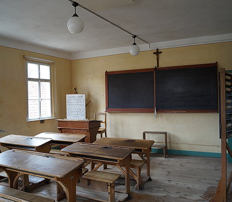 Historisches Klassenzimmer mit Schulbänken, Lehrerpult und Schultafel