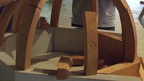 Fotoaufnahme der Führung „Knotenschnur und Zirkelschlag“ in der Spitalkirche. Eine Besuchergruppe baut aus Holzklötzen das Modell eines Gewölbes. Das Modell ist etwa zur Hälfte fertig, in der Mitte liegen noch einige Bauteile.