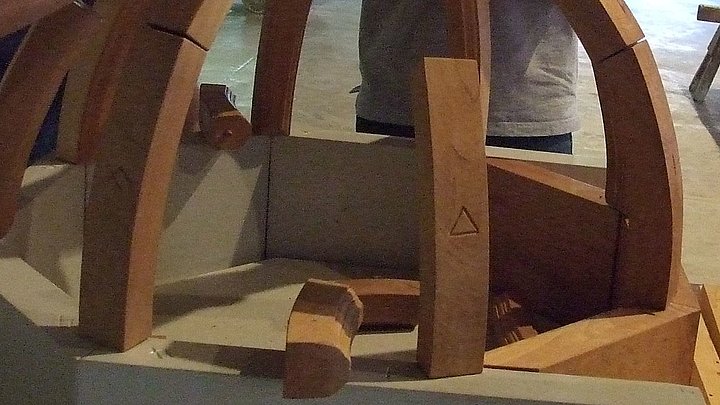 Fotoaufnahme der Führung „Knotenschnur und Zirkelschlag“ in der Spitalkirche. Eine Besuchergruppe baut aus Holzklötzen das Modell eines Gewölbes. Das Modell ist etwa zur Hälfte fertig, in der Mitte liegen noch einige Bauteile.