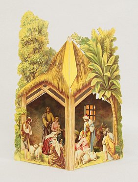 Die Krippe ist aus Papier. Sie wird gefaltet und aufgestellt. Sie zeigt die Geburt Christi. Der Stall ist mit Stroh gedeckt. Im Stall befinden sich mehrere Personen und Tiere.