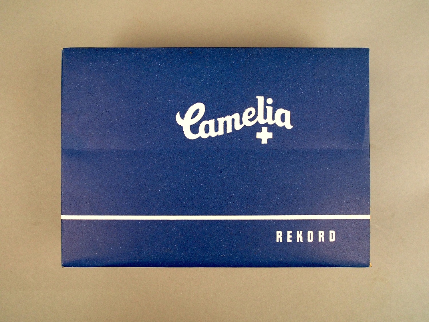 Die Packung ist blau. Auf ihr steht "Camelia". Die Schrift ist weiß. In der Packung sind Damenbinden.