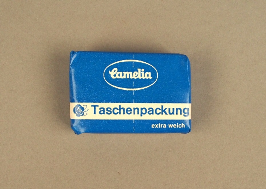 Die kleine Packung ist blau. Die Schrift ist weiß. Auf der Packung steht: "Camelia", und "Taschenpackung".